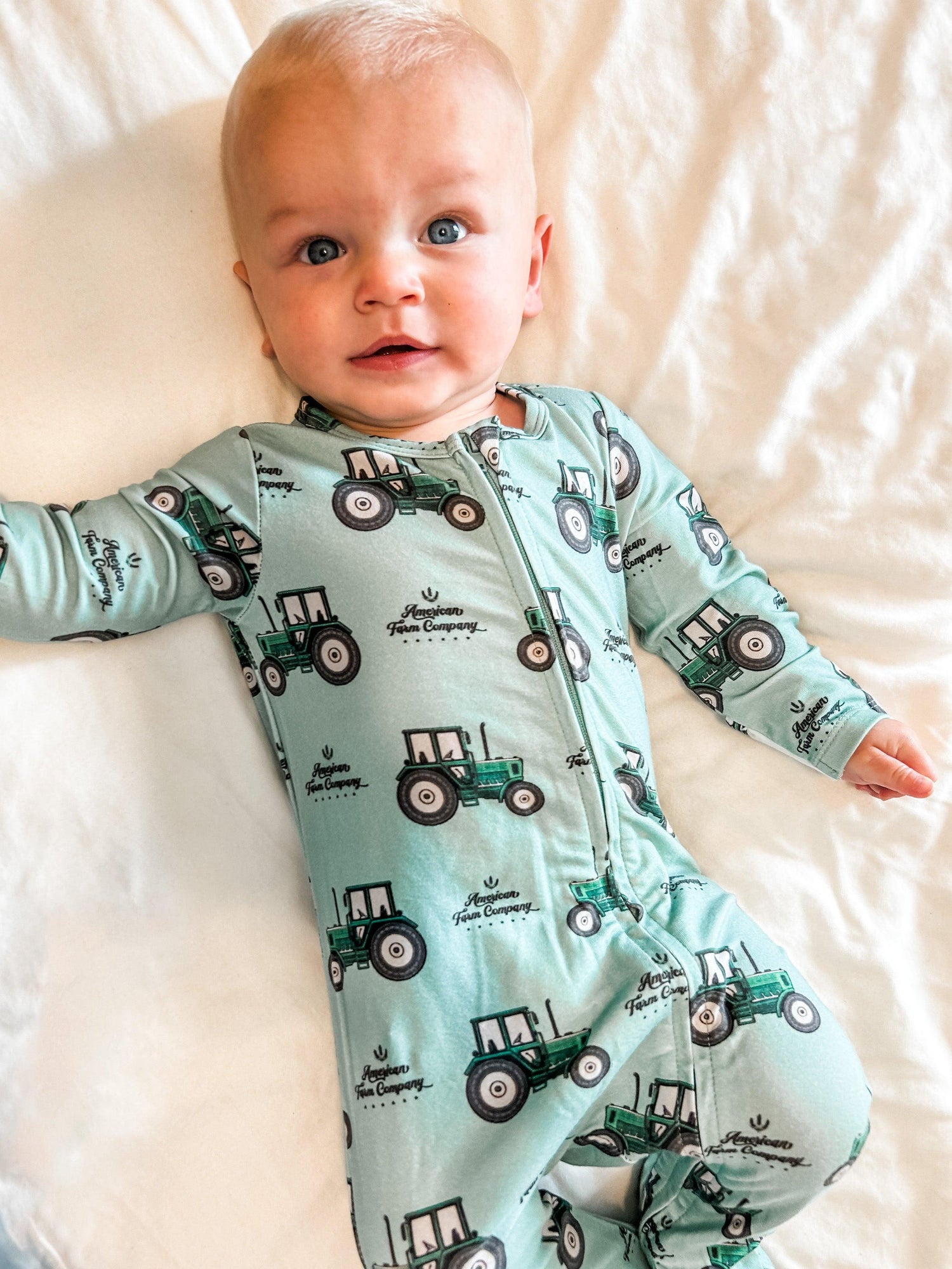 Heritage-inspired mint green baby sleeper with vintage tractor print and American Farm Company motif, soft cotton ideal for rural family lifestyle.