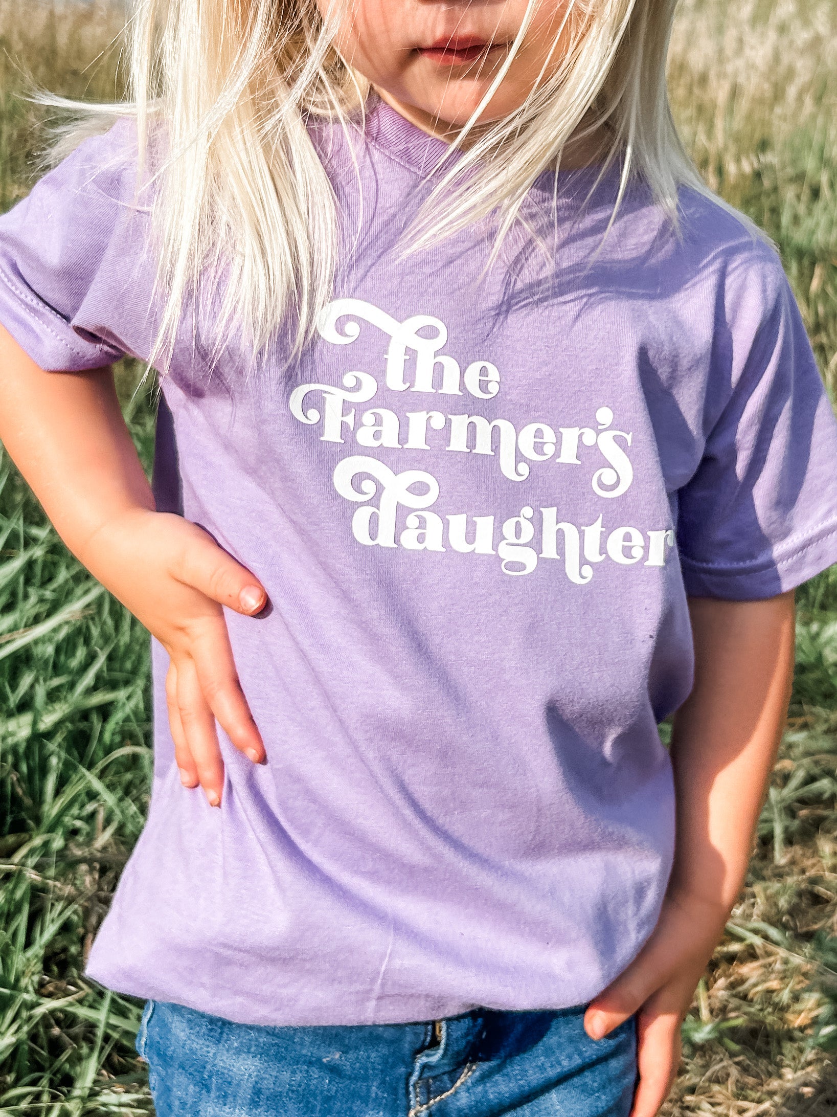 A kid in the field wearing a close up view of The Farmers Daughter Youth and Toddler Onesies in purple