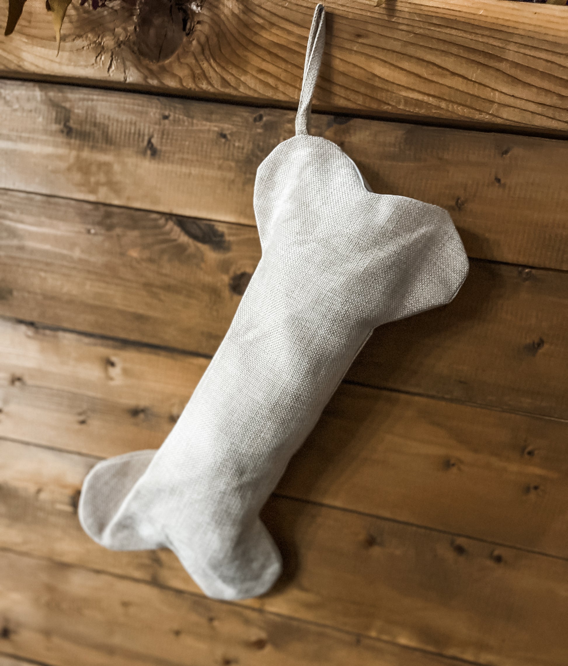 An image of a Dog Bone Christmas Stocking hanging on a decorated wooden surface