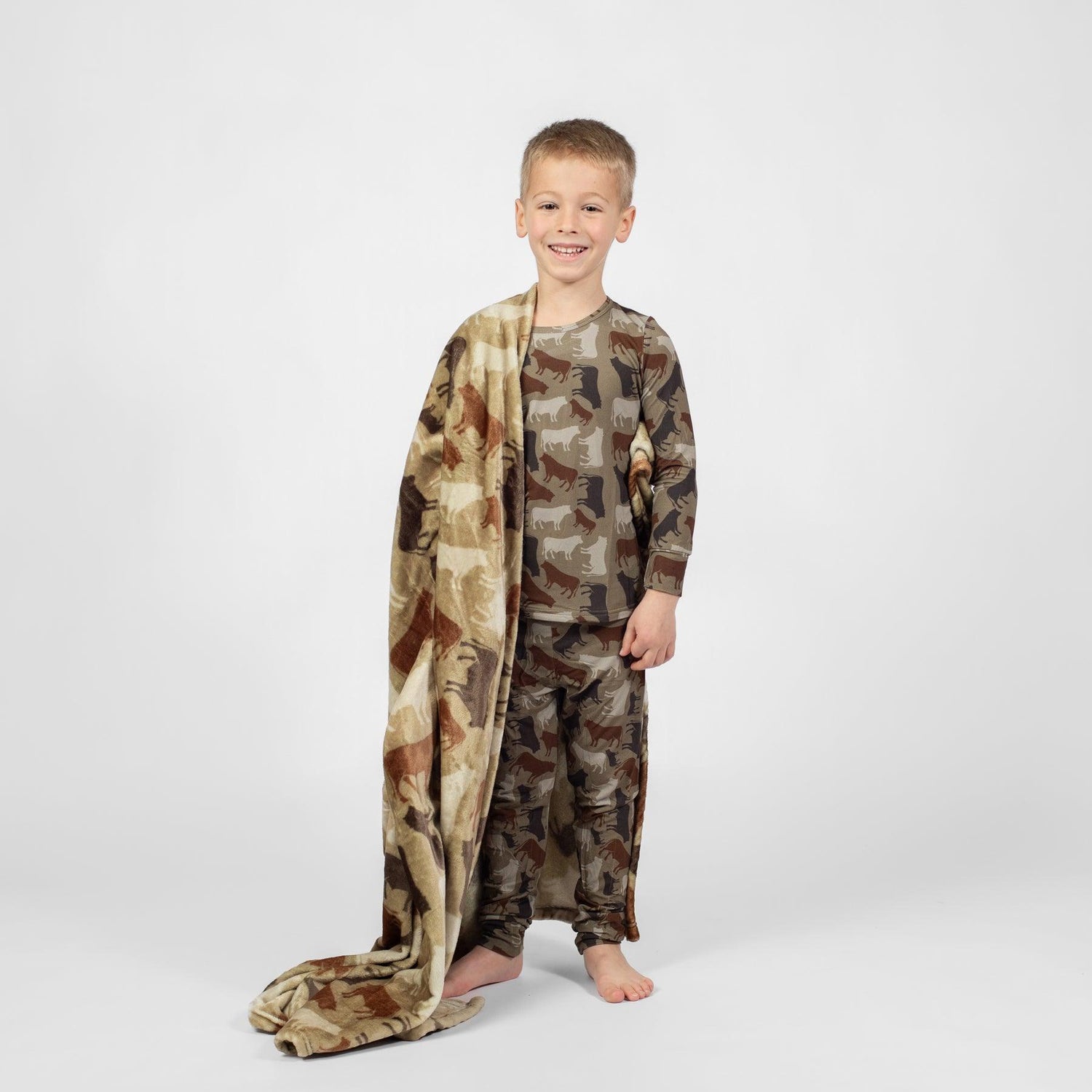 Child in relaxed fit farm animal print pajamas with matching fleece blanket, embodying American Farm Company’s rural heritage lifestyle.