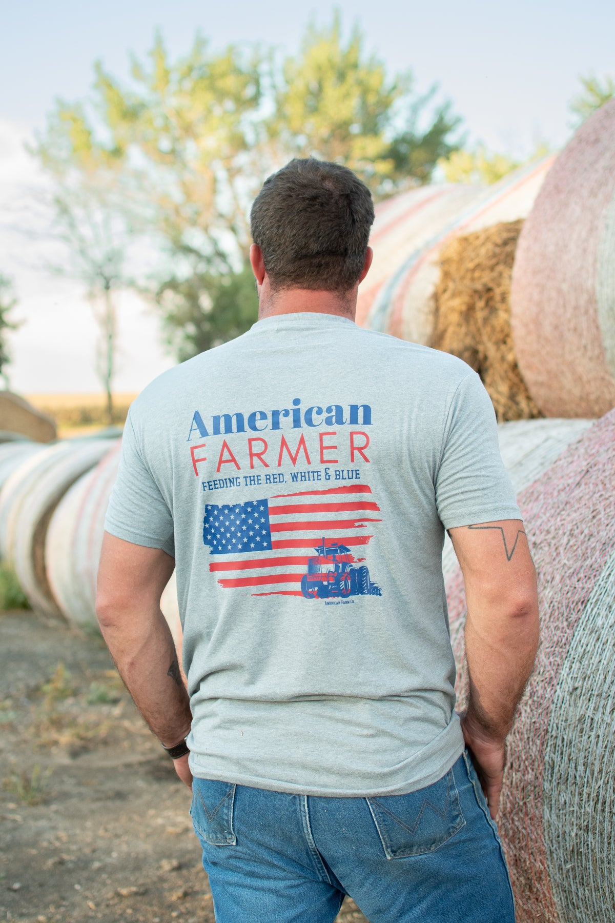 Heritage-inspired grey short sleeve tee with bold American flag and tractor graphic, rugged rural workwear by American Farm Company, perfect for agricultural lifestyle.