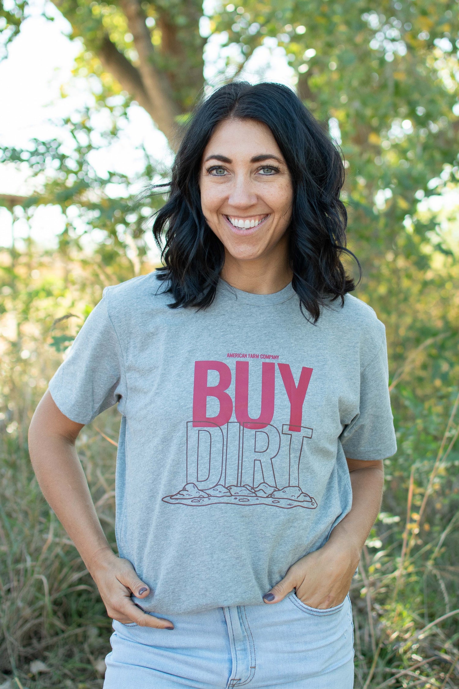 Heather grey relaxed fit tee with bold 'BUY DIRT' graphic, rustic earth motif, embodying rural heritage from American Farm Company.