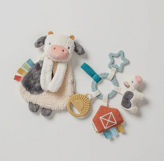 Plush cow security blanket with soft sherpa texture, rainbow tags, and farm-themed baby sensory toys, evoking American Farm Company's heritage rural lifestyle.
