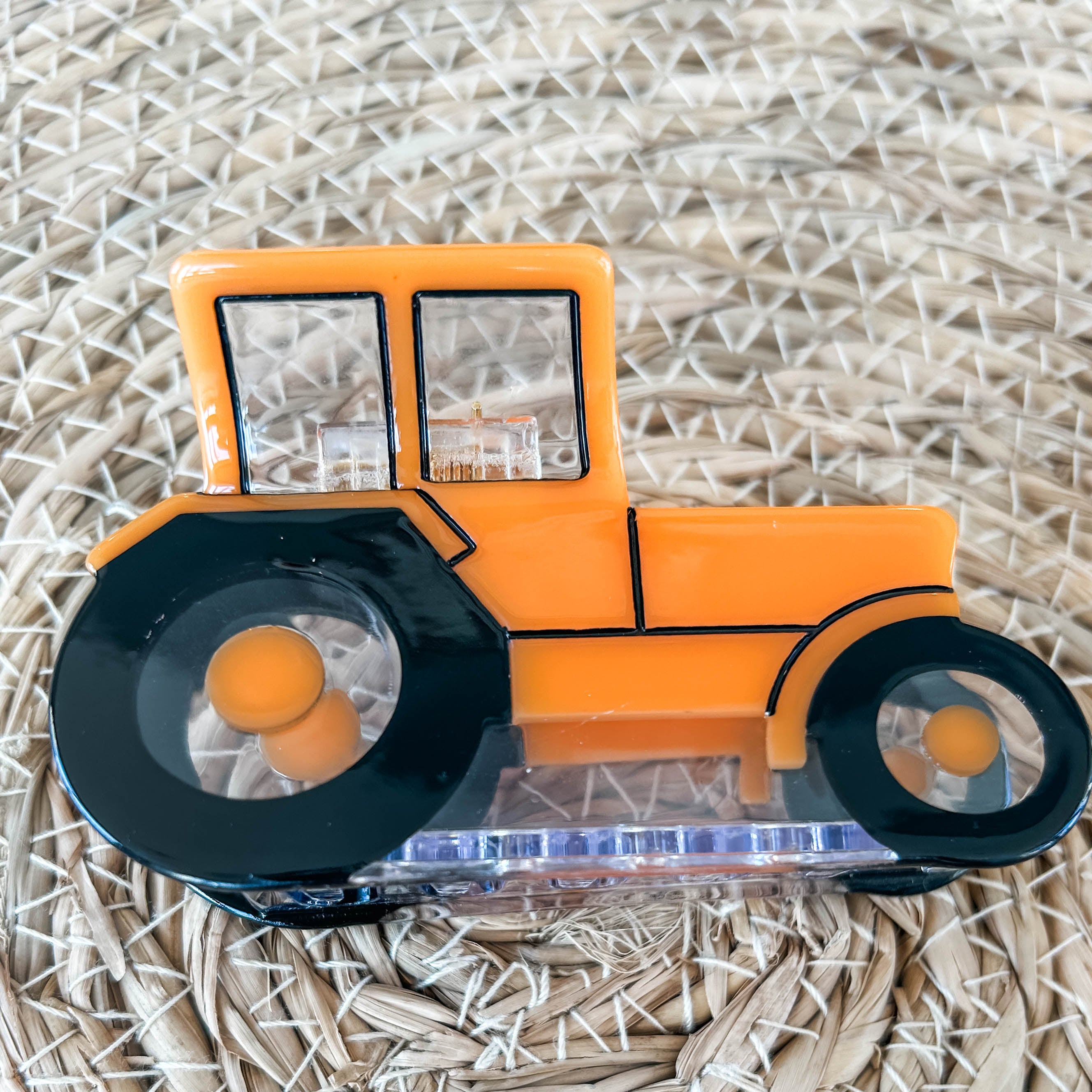 Photograph displaying a side view of an orange tractor claw clip.