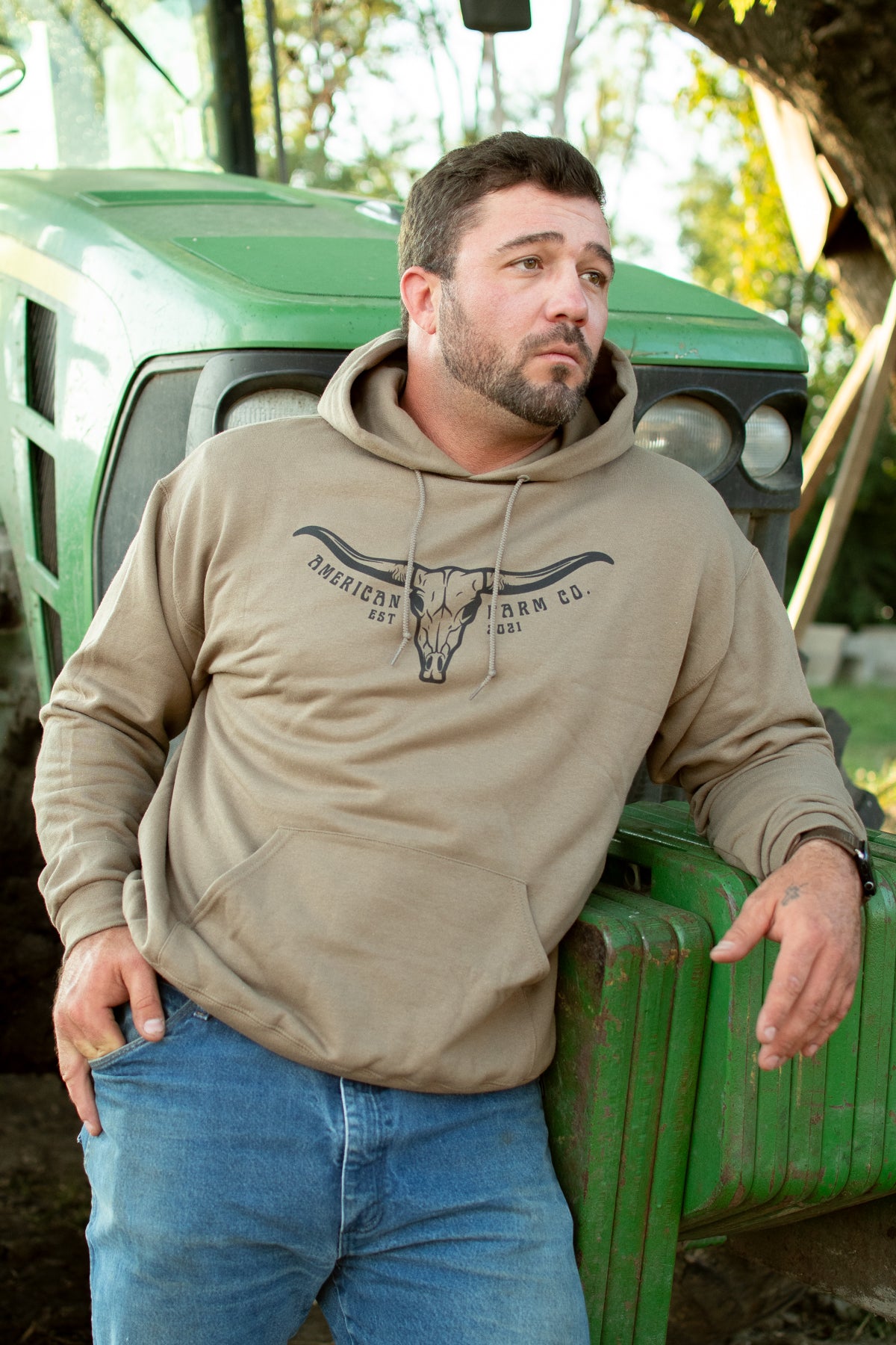 Mocha heavyweight cotton hoodie with longhorn skull graphic and American Farm Co. logo, rural outdoor setting