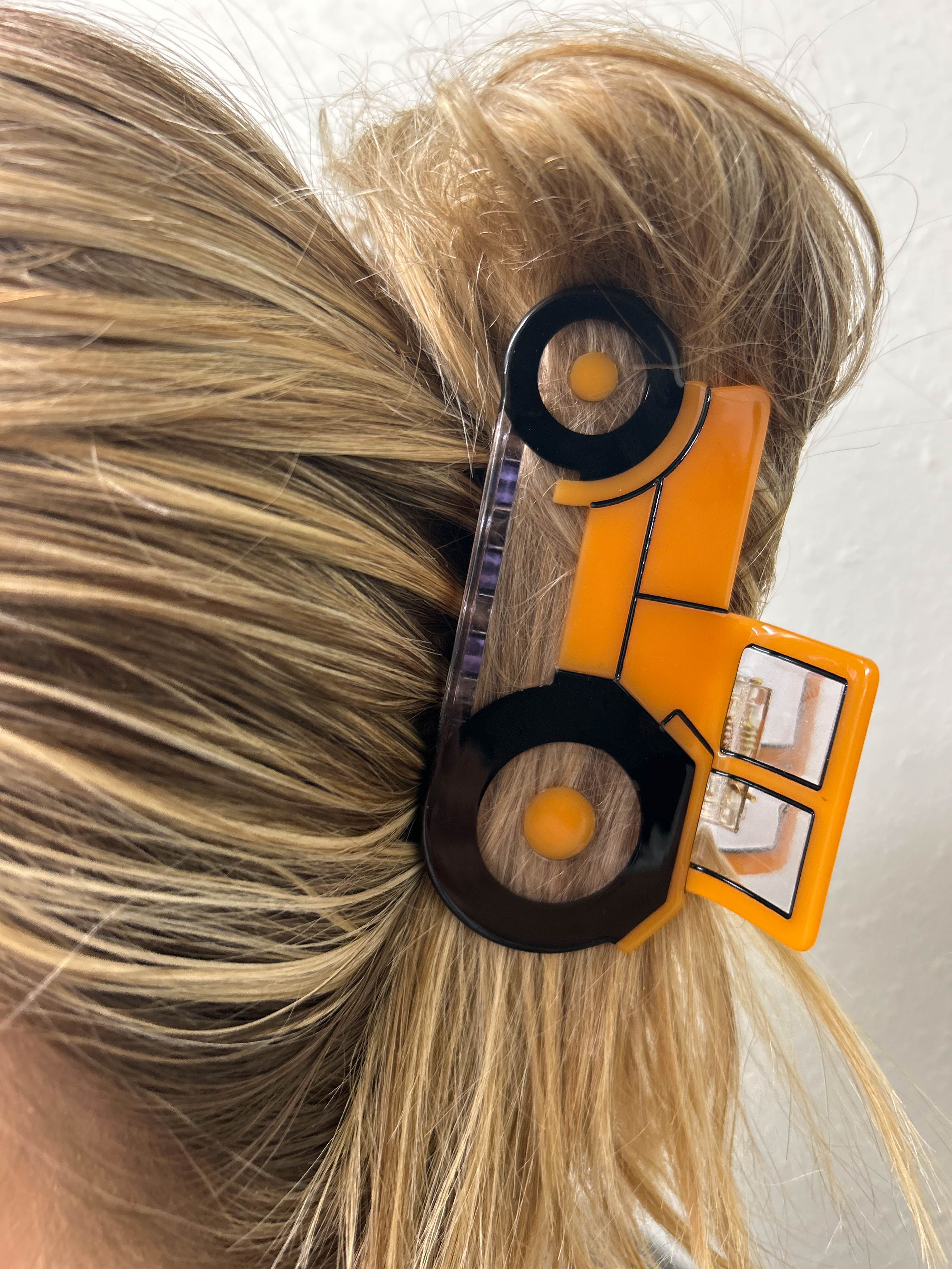 A woman wearing an orange tractor claw clip in her hair