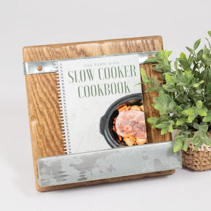 Rustic wood cookbook stand with galvanized accents, holding a slow cooker recipe book, styled beside a woven plant for a modern farmhouse kitchen vibe.