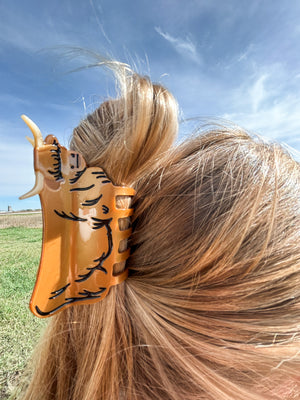 Metallic Highland Cow Claw Clip securing a woman's hair in field