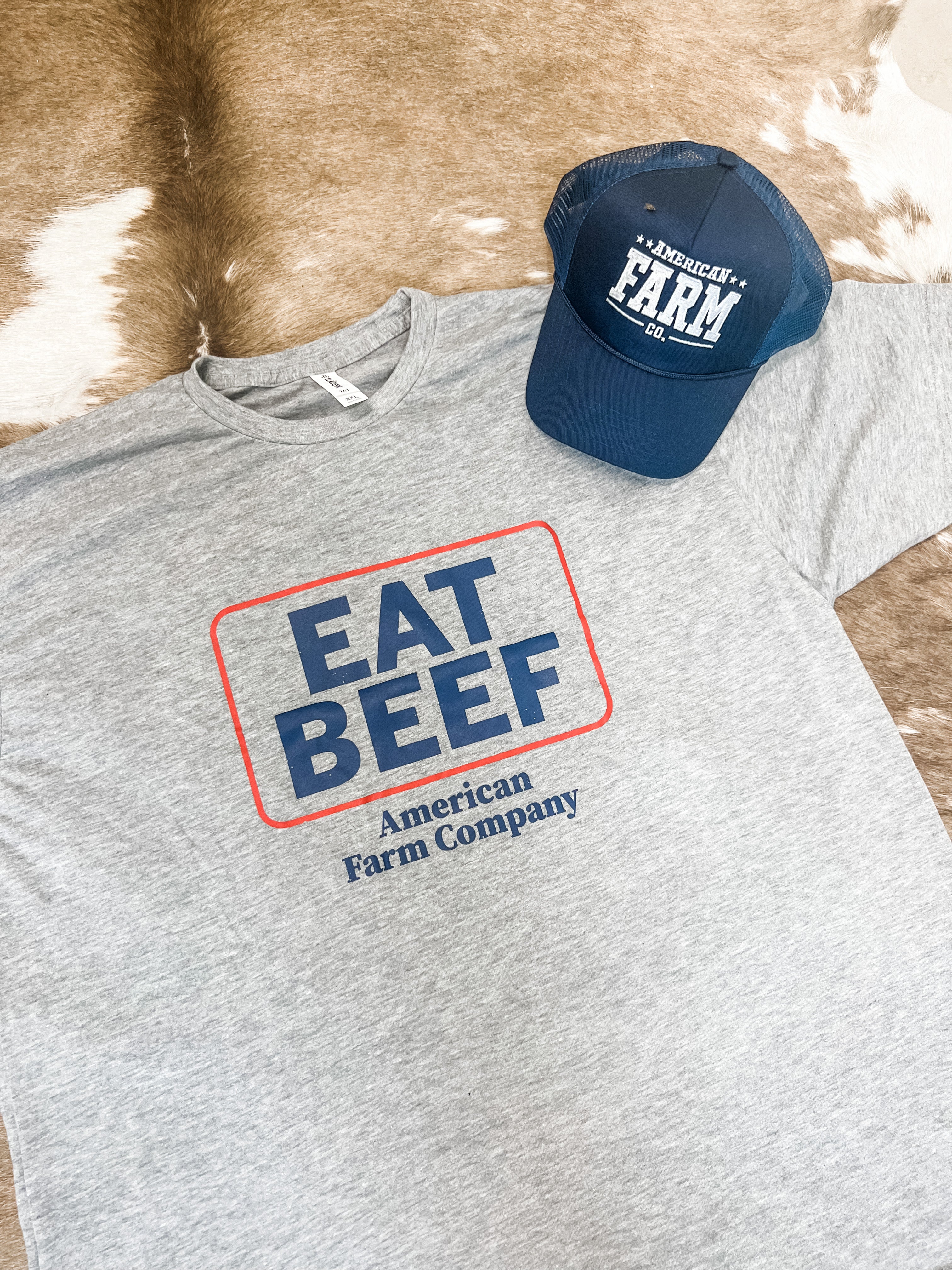 Flat lay of an Eat Beef Shirt with a farm cap placed on the side