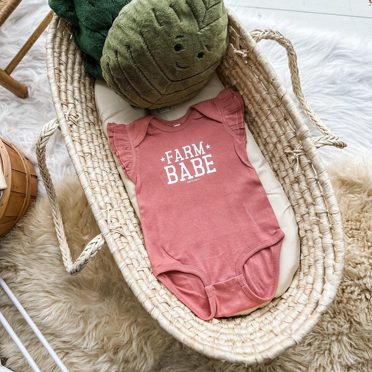 Mauve ruffle sleeve baby onesie in soft cotton with bold white 'Farm Babe' rural graphic, styled for legacy farmstead charm by American Farm Company.