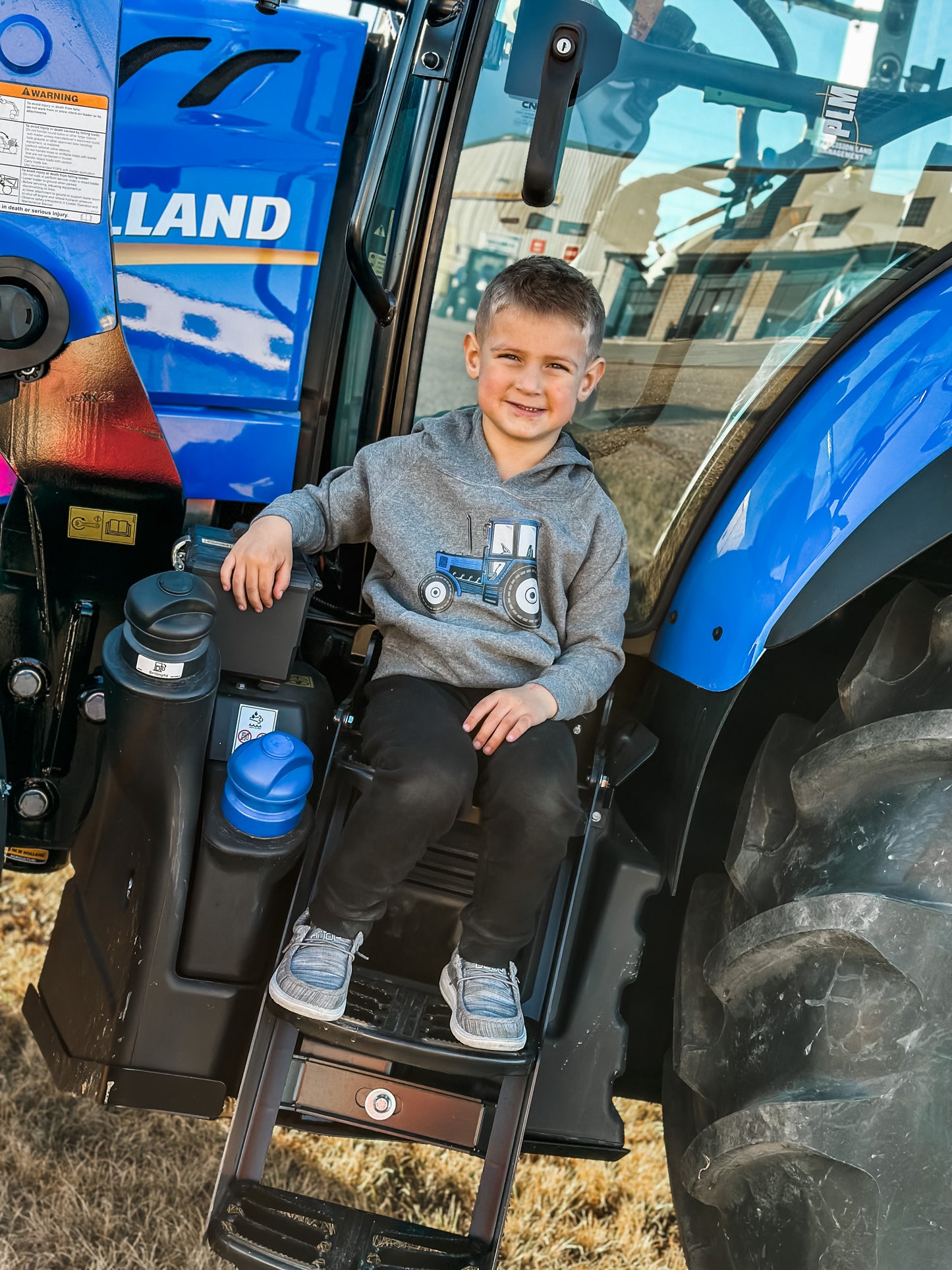 blue tractor hoodie worn by kid on a tractor