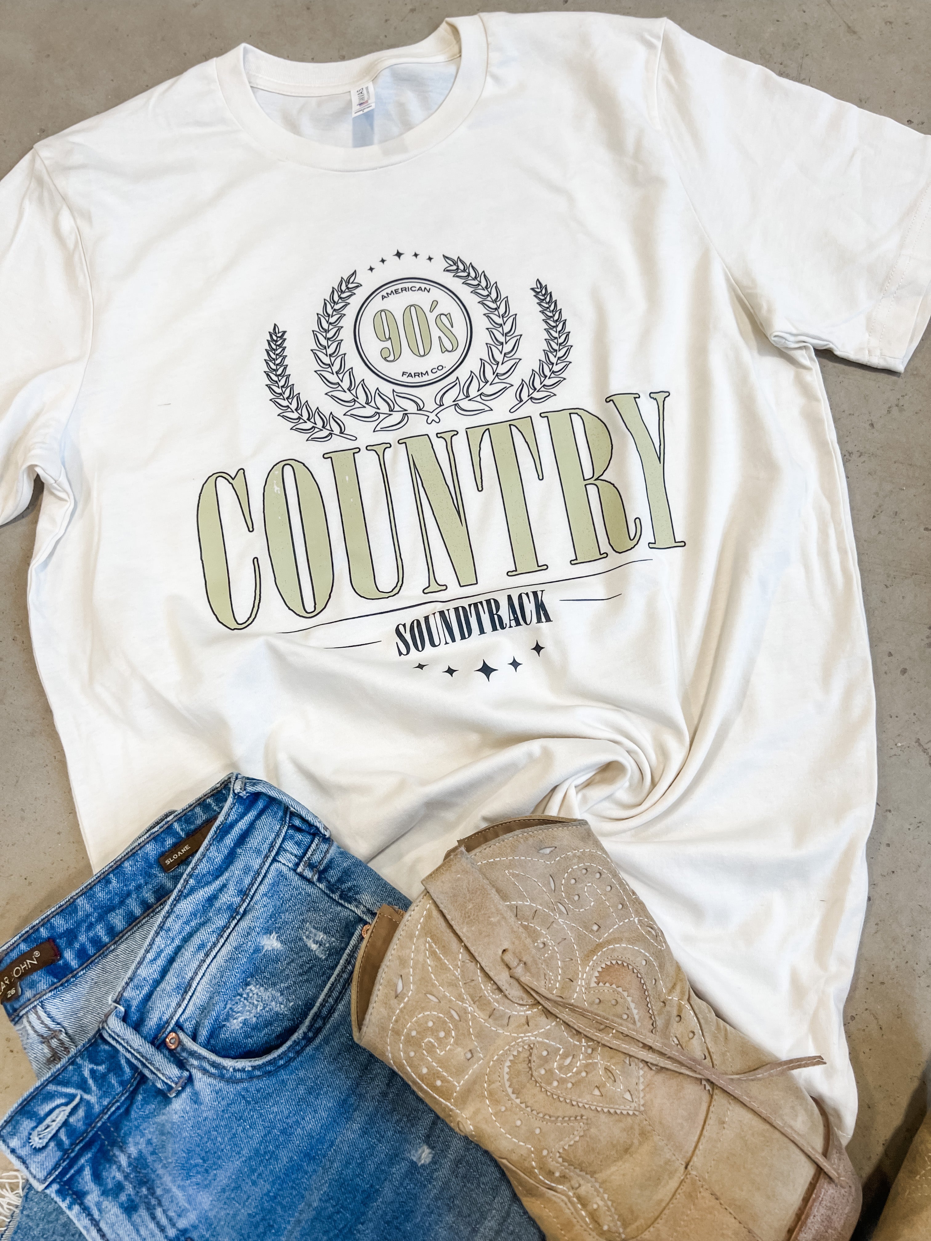 90s Country T-Shirts flat lay with jeans and boots beside