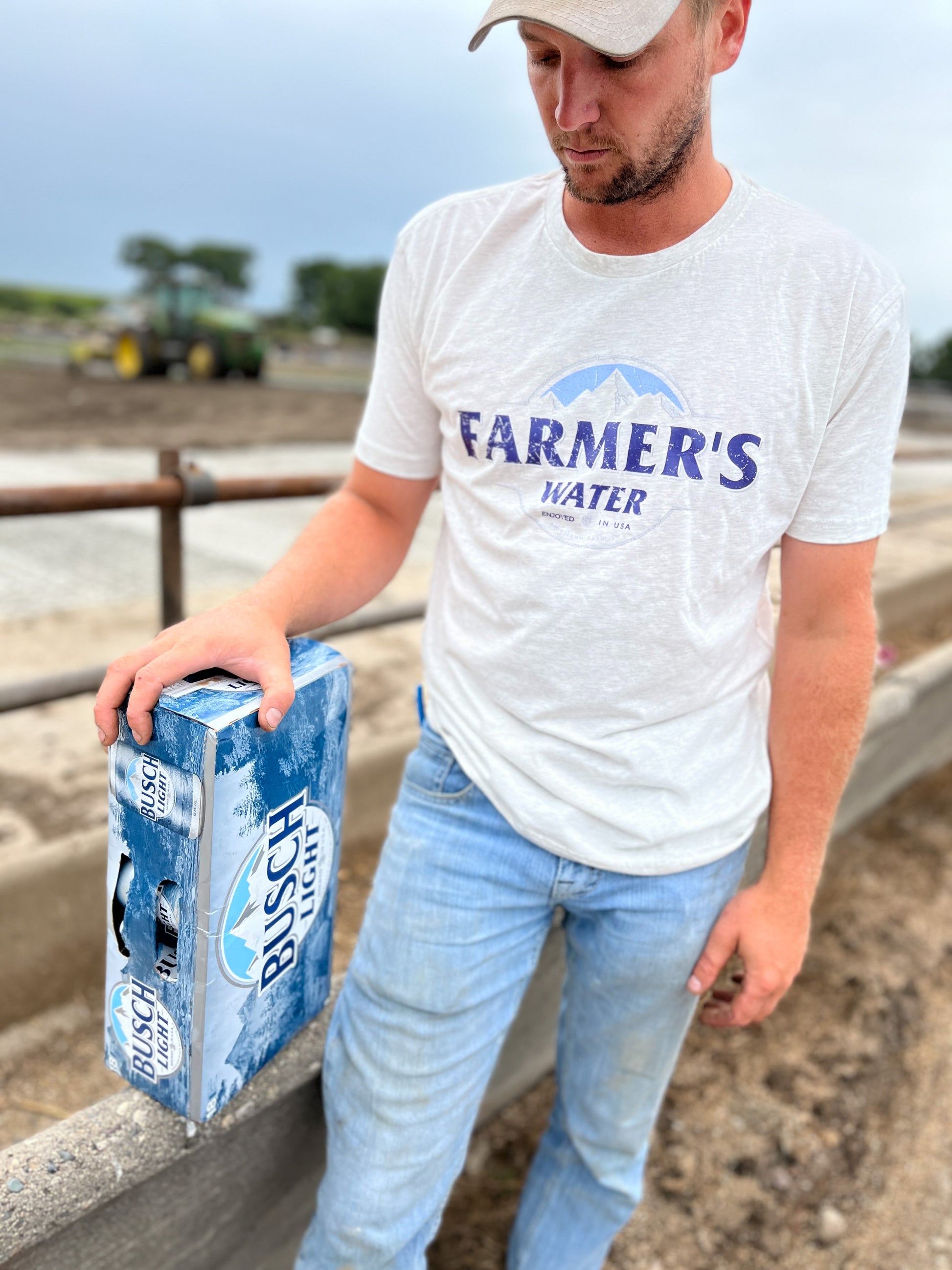 A man wearing a cap and Farmers Water Country Tshirt in the field paired with jeans